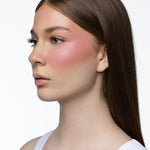 Model wearing MINË Plumping Blush Stick in Pinky Promise