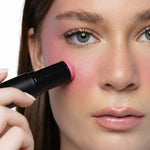 Applying MINË Plumping Blush Stick in Pinky Promise to the cheek