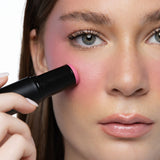 Applying MINË Plumping Blush Stick in Pinky Promise to the cheek