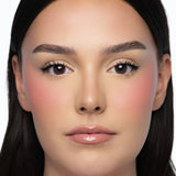 Model wearing MINË Plumping Blush Stick in Peach Melt