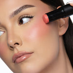 Applying MINË Plumping Blush Stick in Peach Melt to the cheek